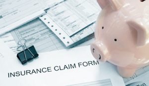 Photo of patient medical bills and insurance claim form, with piggy bank (DepositPhotos 60864455)